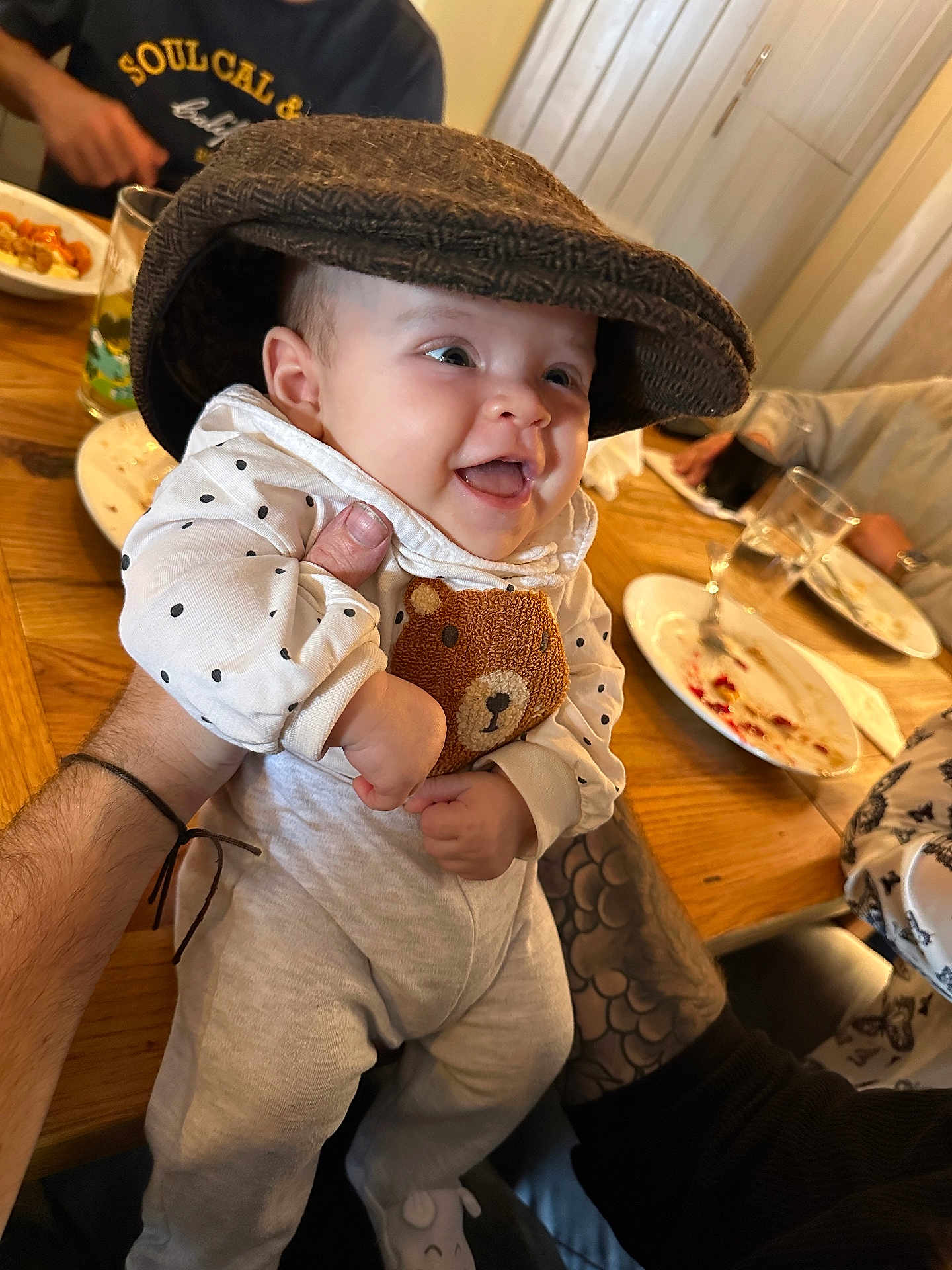 Amara joined the competition — help win amazing prizes! baby, hat, smile, polka_dot, bear, clothing, tattoo, hand, table, glass, plate, food, dining, happy, person, indoor, cute, infant, sitting, family