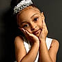 Myara is registered to the contest to win money with this photo: child, girl, portrait, face, hands, tiara, dress, white_dress, pearl_necklace, smile, brown_eyes, hair_bun, elegant, studio, pose, young, fashion, cute, beauty, innocence