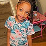 Myara is registered to the contest to win money with this photo: child, girl, braids, beads, floral_clothing, indoor, smile, pillow, carpeted_stairs, table, chairs, wooden_floor, water_bottle, playful, cute, person, home, happy, portrait, young