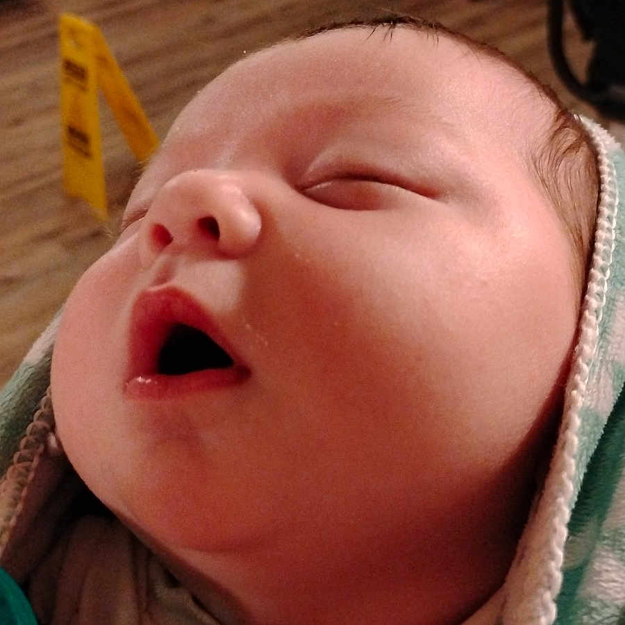 Auriah is registered to the contest to win money with this photo: baby, blanket, blurred_background, caution_sign, child, close_up, cozy, face, indoors, infant, mouth_open, newborn, pacifier, peaceful, portrait, resting, sleeping, soft_texture, wooden_floor, wrapped