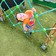 Stylia participe au concours pour gagner de l'argent avec cette photo : active, casual_clothing, child, climbing, daylight, fun, grass, greenery, happy, orange_shirt, outdoor, play, playground, recreation, rope_net, shorts, smiling, sport, wooden_structure, young_child