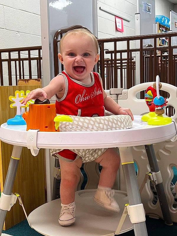 Koda is registered to the contest to win money with this photo: baby, baby_products, baby_toddler_clothing, chair, child, flooring, fun, person, play, room, shorts, sitting, smile, t_shirt, table, thigh, toddler, toy, toy_vehicle, white
