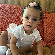 Star is registered to the contest to win money with this photo: toddler, child, baby, crawling, headband, flower, white_shirt, socks, sofa, cushion, blanket, curtains, indoors, portrait, cute, curly_hair, looking, hands, floor, cozy