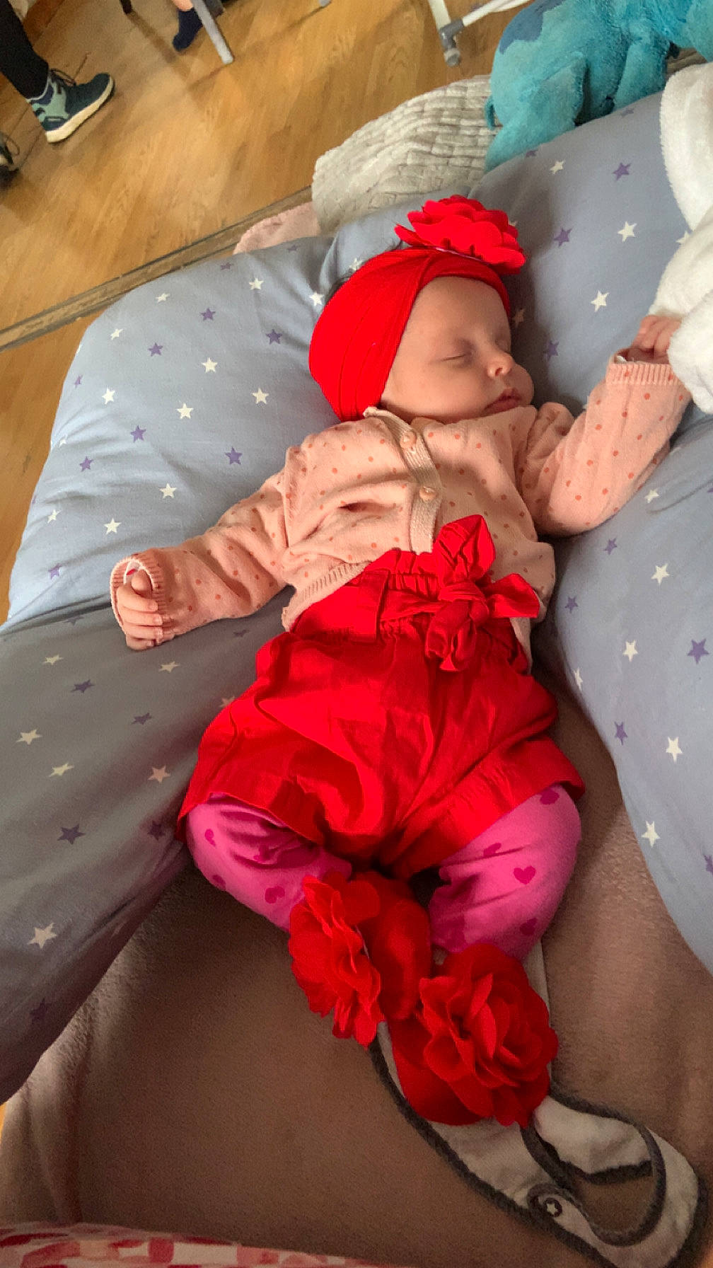 baby, blanket, child, comfort, cozy, cute, floor, flower_accessory, footwear, headband, indoors, infant, pillow, pink_clothing, red_clothing, resting, sleeping, soft_fabric, star_pattern, toddler