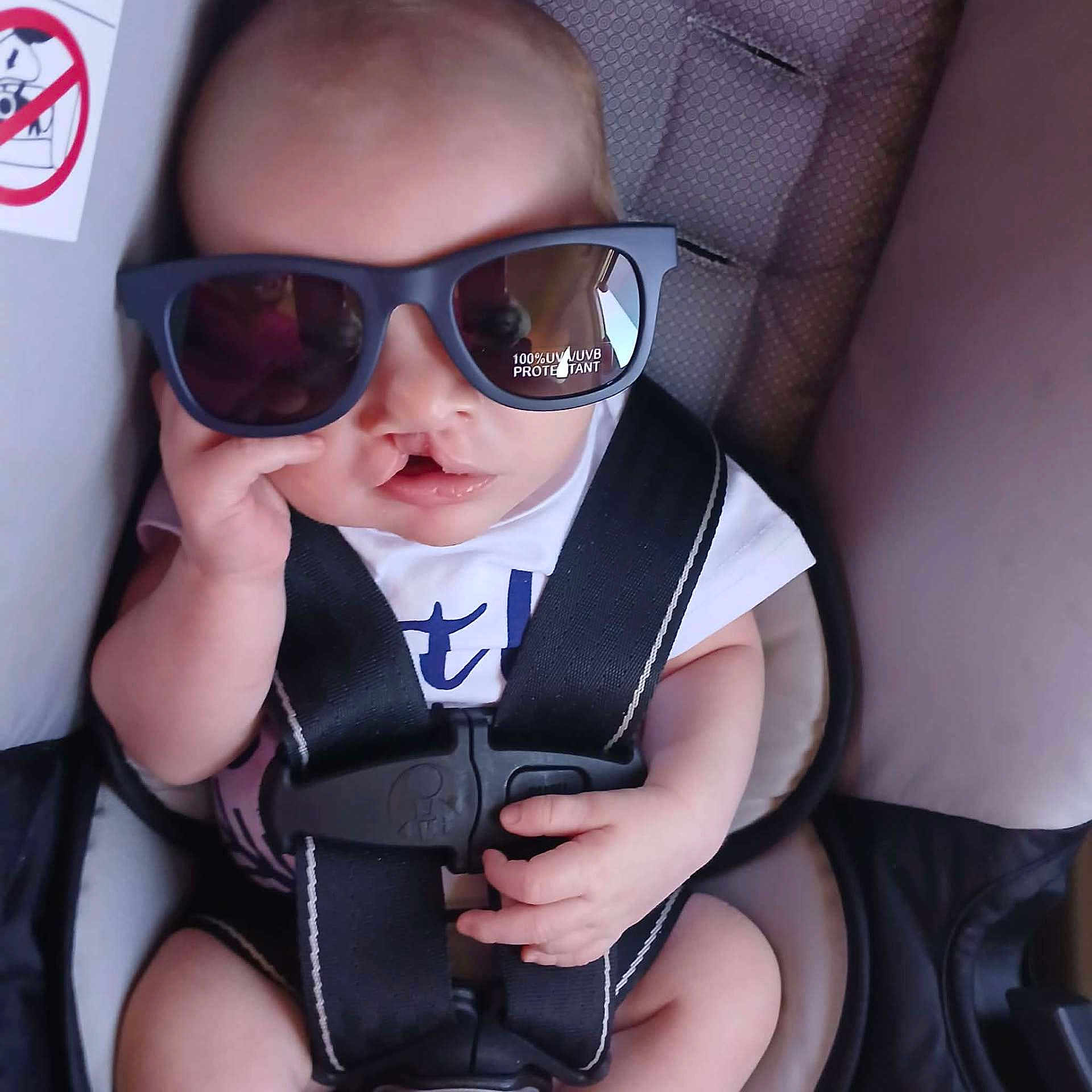 Jasper joined the competition — help win amazing prizes! baby, child, sunglasses, car_seat, seatbelt, infant, person, cute, fashion, accessory, clothing, hand, face, head, seat, safety, young, cool, portrait, indoor