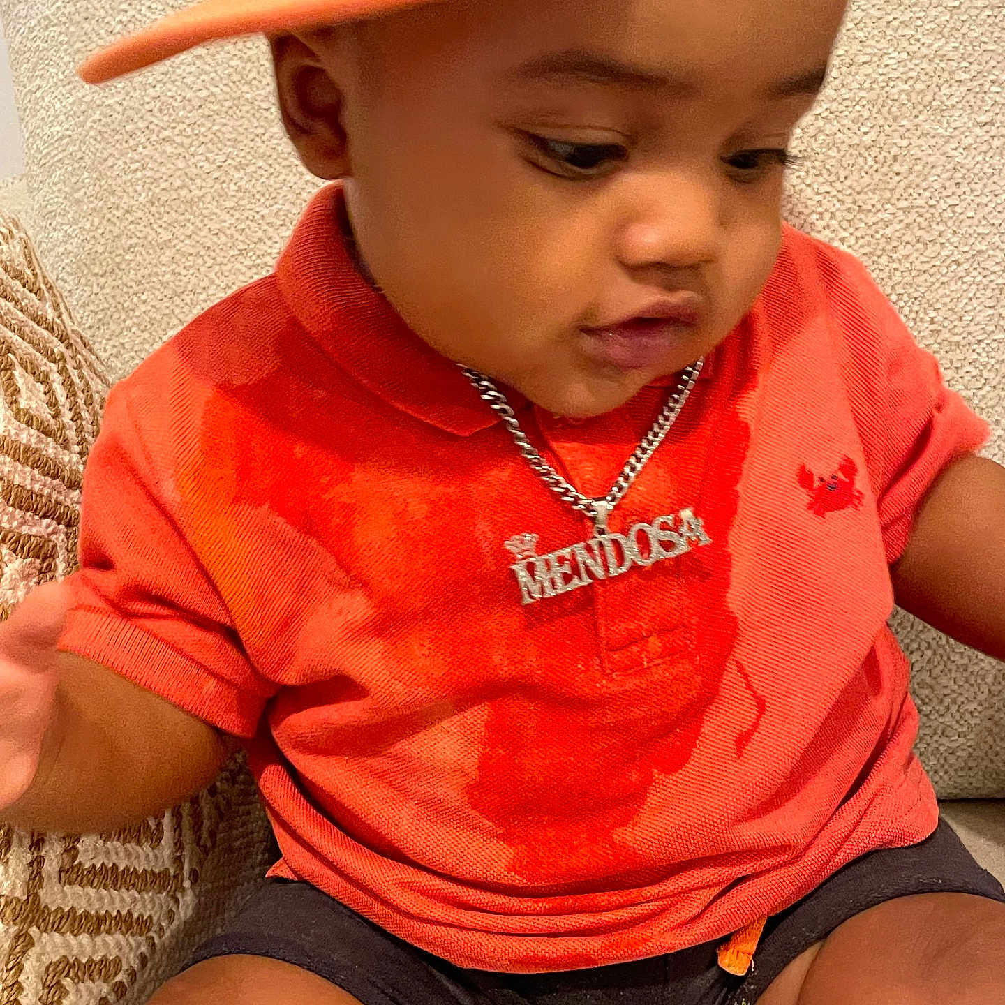 Raheem participe au concours pour gagner de l'argent avec cette photo : toddler, child, cap, orange_shirt, necklace, silver_chain, sitting, indoor, couch, curious, cute, baby, person, portrait, clothing, fabric_texture, headwear, shorts, skin, young_child