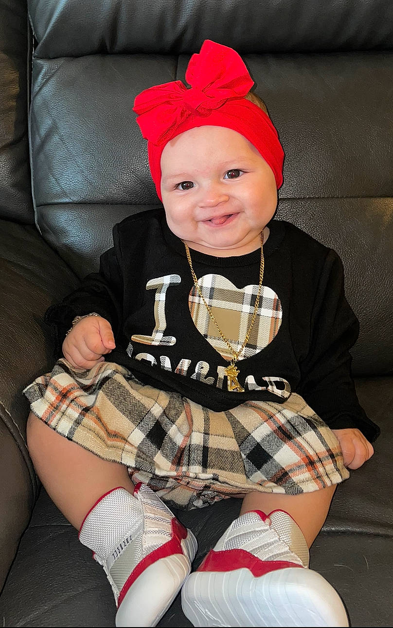 Annalise joined the competition — help win amazing prizes! baby, baby_toddler_clothing, comfort, headwear, human_body, human_leg, joy, knee, lap, leg, pattern, person, pink, plaid, red, sleeve, smile, sock, tartan, textile