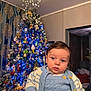 baby, child, christmas_tree, blue_lights, holiday, indoors, cozy_clothing, sweater, decorations, ornaments, festive, portrait, home, curious, seasonal, celebration, cute, young_child, face, winter
