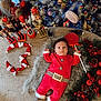 baby, christmas, holiday, festive, nutcracker, lollipop, santa_claus_costume, decorations, christmas_tree, lights, ornaments, wreath, pinecones, red_berries, fur_rug, toy, infant, holiday_spirit, cute, indoor