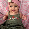 baby, child, smiling, headband, flower, dress, green_dress, pink_background, portrait, happy, cute, infant, sitting, hands, face, eyes, skin, apparel, fabric, indoors