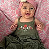 baby, child, smiling, headband, flower, dress, green_dress, pink_headband, patterned_blanket, happy, portrait, infant, sitting, cute, closeup, indoors, person, young_child, apparel, accessory