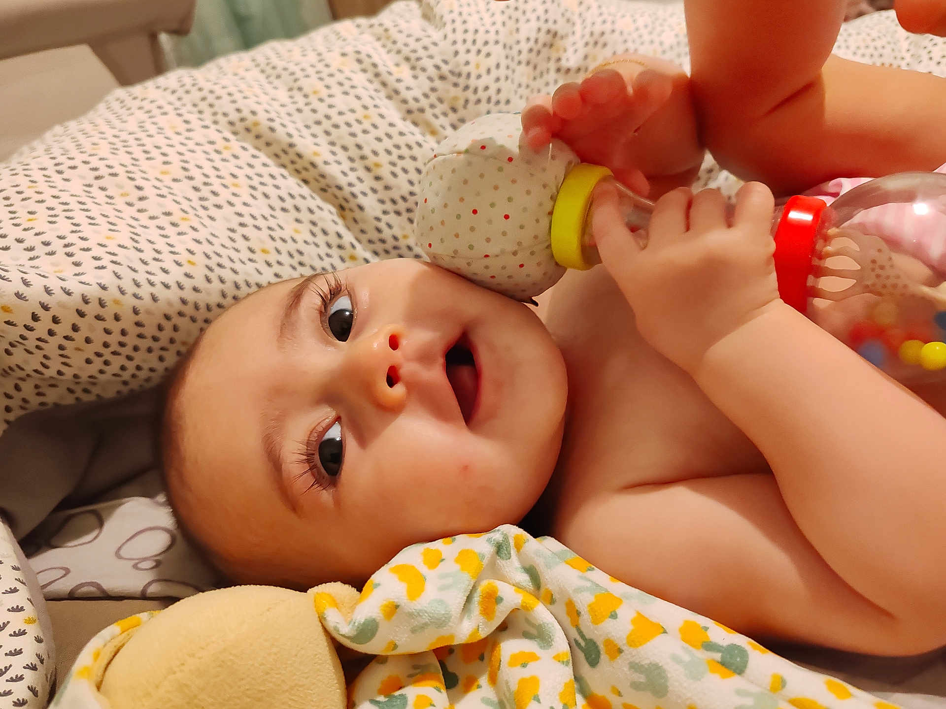 Assyle a rejoint le concours — aidez-le/la à gagner de superbes lots ! baby, infant, blanket, toy, rattle, hand, foot, face, eyes, curious, lying_down, bed, cushion, soft_toy, child, cute, indoors, skin, playful, young