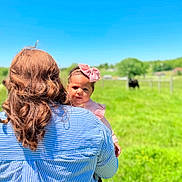 Eliza joined the competition — help win amazing prizes! baby, blue_sky, bow, child, cow, curly_hair, daylight, field, grass, greenery, headband, holding, nature, outdoor, pasture, person, portrait, striped_shirt, sunny, woman