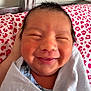 Ismael joined the competition — help win amazing prizes! newborn, baby, smiling, swaddled, blanket, close_up, infant, cute, happy, face, person, indoors, head, skin, pink, pattern, fabric, sleepy, resting, cozy