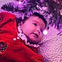baby, child, red_dress, lace, face, portrait, indoor, soft_lighting, purple_light, blanket, cozy, cute, infant, smiling, closeup, holiday_theme, decor, soft_texture, young_child, happy