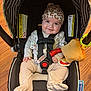 baby, car_seat, infant, smiling, pajamas, hat, plush_toy, pacifier, seatbelt, wooden_floor, indoors, child, cute, safety, comfort, patterned_clothing, headwear, baby_accessories, young_child, happy