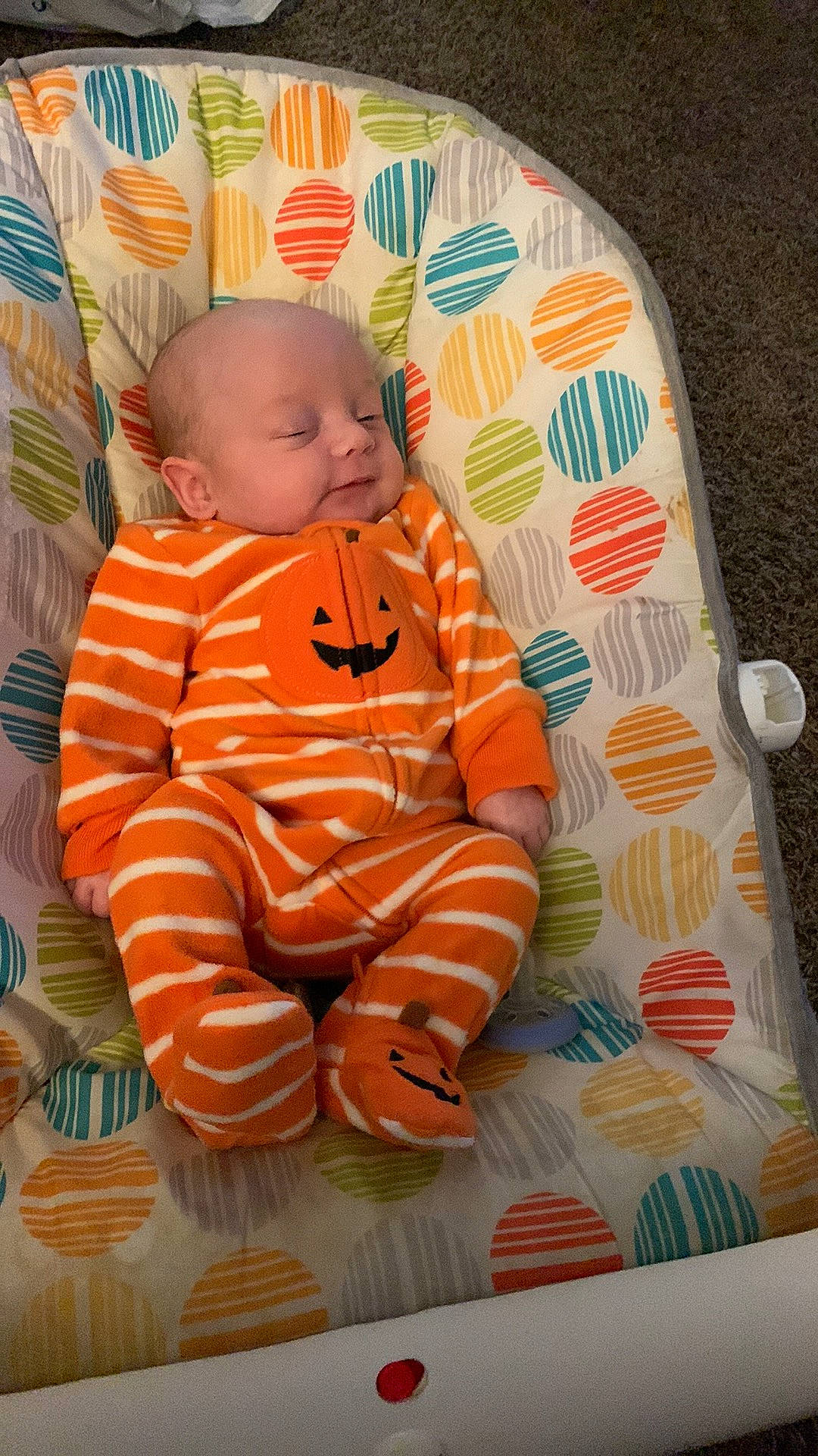 Ethan is registered to the contest to win money with this photo: art, baby, baby_toddler_clothing, brown, cheek, comfort, eye, flooring, head, linens, nose, orange, pattern, person, pink, product, sitting, skin, sleeve, textile