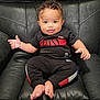 baby, child, infant, black_leather_chair, clothing, sportswear, smile, barefoot, curly_hair, sitting, cute, portrait, indoor, person, young_child, happy, face, small_hands, small_feet, comfortable