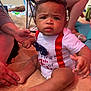 Emir joined the competition — help win amazing prizes! baby, child, beach, sand, onesie, bow_tie, red_suspender, person, legs, hand, summer, outdoor, skin, foot, toes, expression, sitting, clothing, vacation, daylight