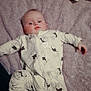 baby, onesie, blanket, purple, lying_down, infant, cute, cartoon_bear, sleepwear, soft_texture, child, indoor, foot, face, pajamas, cozy, relaxed, sleeping_area, fabric, person