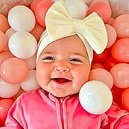 Quinn joined the competition — help win amazing prizes! baby, bow, headband, pink, white, balls, smile, happy, child, infant, cute, play, toy, soft, zipper, face, clothing, cheerful, indoors, closeup