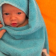 Elya participe au concours pour gagner de l'argent avec cette photo : baby, blue_towel, face, infant, wrapped, curious, orange_background, soft_texture, newborn, child, portrait, cute, skin, hand, warm, cozy, closeup, expression, person, indoors