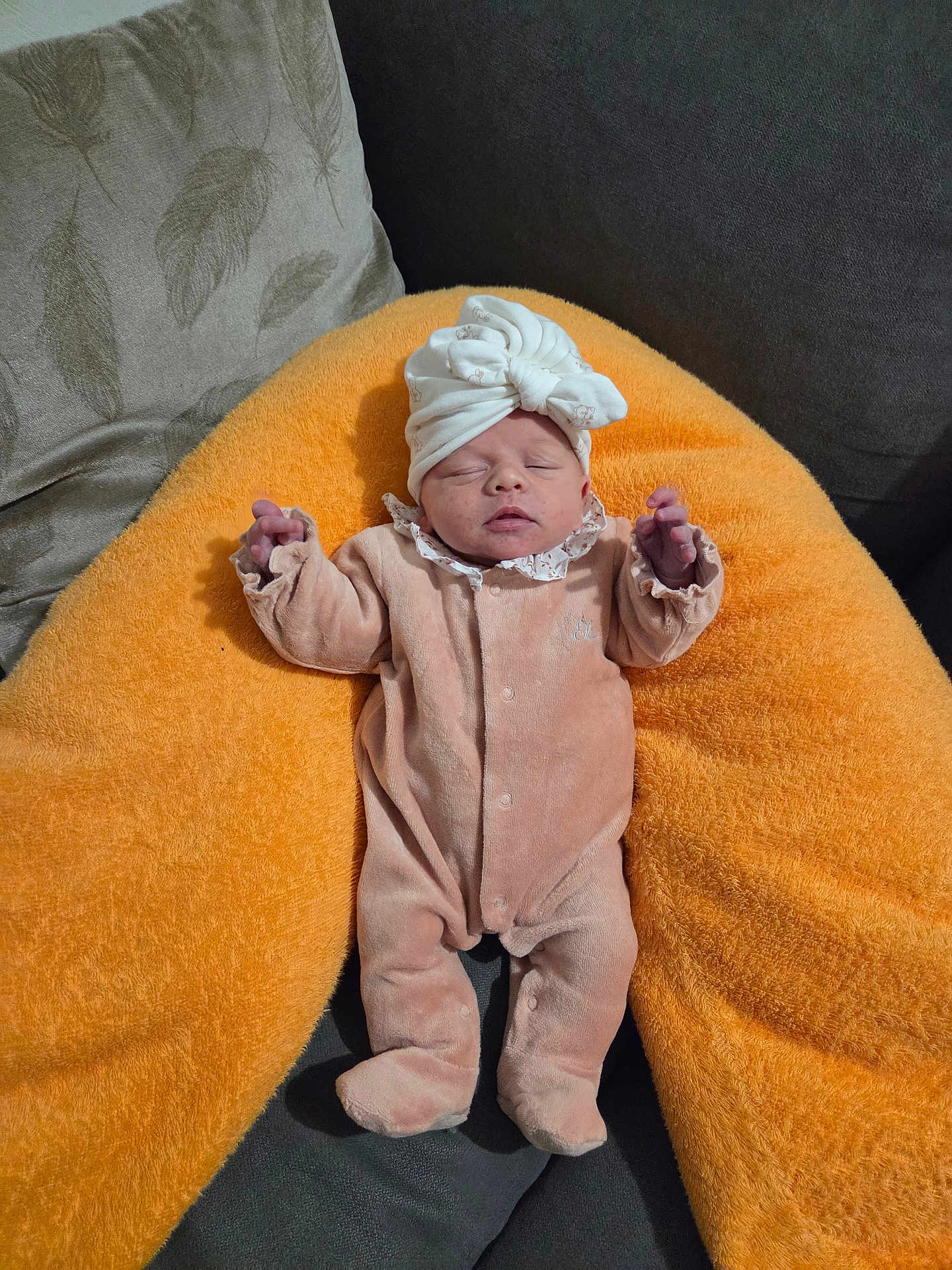 Elya a rejoint le concours — aidez-le/la à gagner de superbes lots ! baby, newborn, infant, hat, bow, onesie, cushion, pillow, orange, sofa, couch, sleeping, sleepy, cozy, tiny_hands, closed_eyes, headwear, living_room, soft_texture, portrait