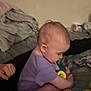 Kienna joined the competition — help win amazing prizes! baby, child, purple_onesie, toy, bed, blanket, indoor, infant, person, hand, foot, playing, candid, soft_lighting, cozy, furniture, closeup, young_child, seated, focus
