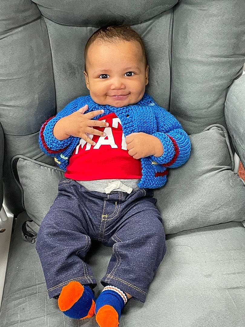 Julius is registered to the contest to win money with this photo: arm, azure, baby, baby_toddler_clothing, blue, cheek, comfort, eye, finger, happy, joy, lap, leg, mouth, person, purple, skin, sleeve, smile, standing