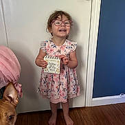 Aradhana joined the competition — help win amazing prizes! child, girl, glasses, dress, floral, barefoot, wooden_floor, door, dog, pet, indoor, sign, smiling, happy, holding, curly_hair, pink, home, cute, person
