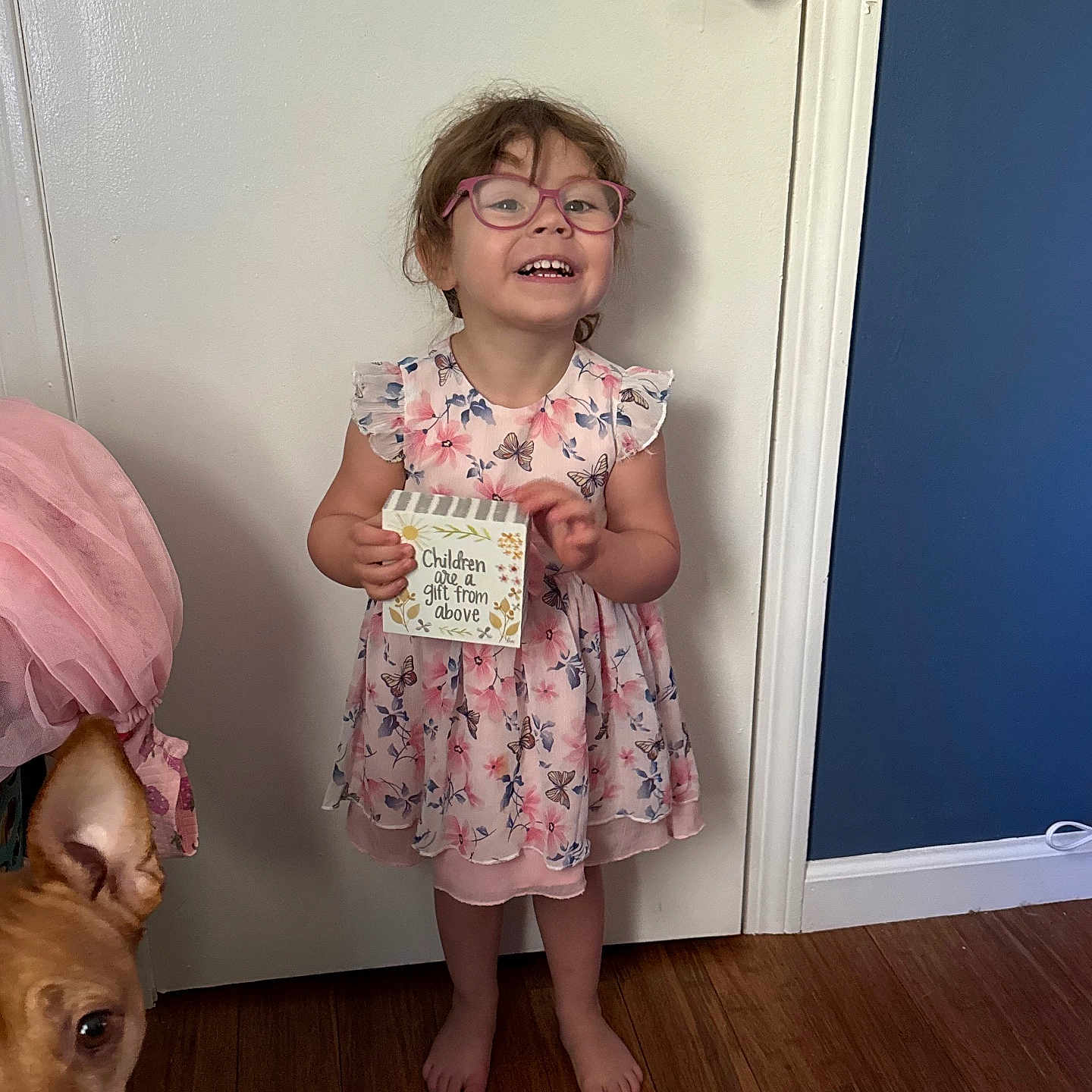 Aradhana joined the competition — help win amazing prizes! barefoot, child, curly_hair, cute, dog, door, dress, floral, girl, glasses, happy, holding, home, indoor, person, pet, pink, sign, smiling, wooden_floor