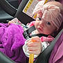 baby, car_seat, child, blanket, purple, headband, pink, seatbelt, car_interior, face, hand, clothing, sitting, portrait, infant, indoor, safety, cute, expression, toy