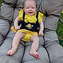 baby, child, smiling, outdoor, chair, cushion, yellow_dress, bee_pattern, happy, person, grass, plush, seat, infant, cute, legs, feet, summer, garden, sunlight