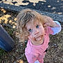 blonde_hair, blue_eyes, casual_clothing, child, curly_hair, cute, daylight, dirty_face, expression, grass, innocent, looking_up, messy, nature, outdoor, pavement, person, pink_clothing, shadow, toddler