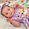 Celia joined the competition — help win amazing prizes! baby, infant, child, portrait, lying_down, purple_outfit, dress, bow, headband, teddy_bear, stuffed_animal, floral_bedding, bed, indoors, wide_eyes, smiling, hands, arms, close_up, colorful
