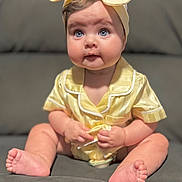 Ilaria is registered to the contest to win money with this photo: baby, infant, blue_eyes, headband, bow, yellow_outfit, sitting, couch, sofa, chubby_cheeks, portrait, face, hands, feet, barefoot, cute, curious_expression, soft_lighting, shallow_depth_of_field, indoor