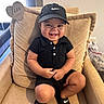 toddler, child, smiling, black_clothing, nike_cap, nike_slides, armchair, indoor, happy, cute, portrait, sitting, baby, footwear, foot, furniture, person, human, cushion, home
