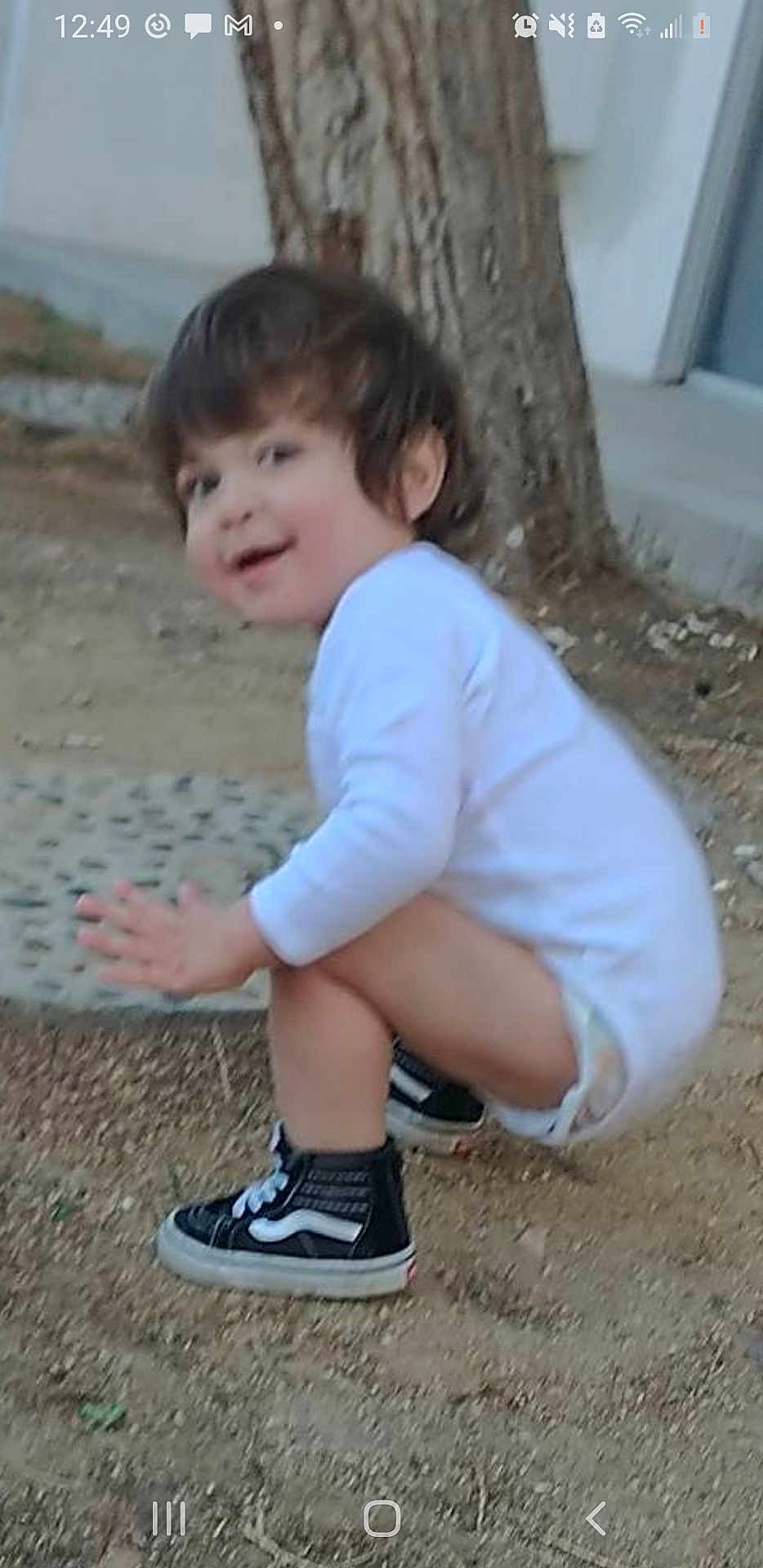 Cuauhtemoc joined the competition — help win amazing prizes! child, sneakers, tree, outdoor, smile, white_shirt, dirt_ground, young_child, crouching, black_shoes, shorts, playful, nature, person, side_view, daylight, casual_clothing, young_kid, hair, face