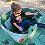 Cuauhtemoc is registered to the contest to win money with this photo: child, sunglasses, toy_tank, outdoor, gravel, shorts, tshirt, spiderman, vehicle, green, sunlight, play, kid, casual_clothing, hand, footwear, seat, tank, summer, young