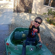 Cuauhtemoc joined the competition — help win amazing prizes! child, sunglasses, toy, tank, playful, backyard, gravel, fence, window, plant, casual_clothing, spiderman, tshirt, tongue_out, gesture, sunlight, shadow, outdoor, person, fun