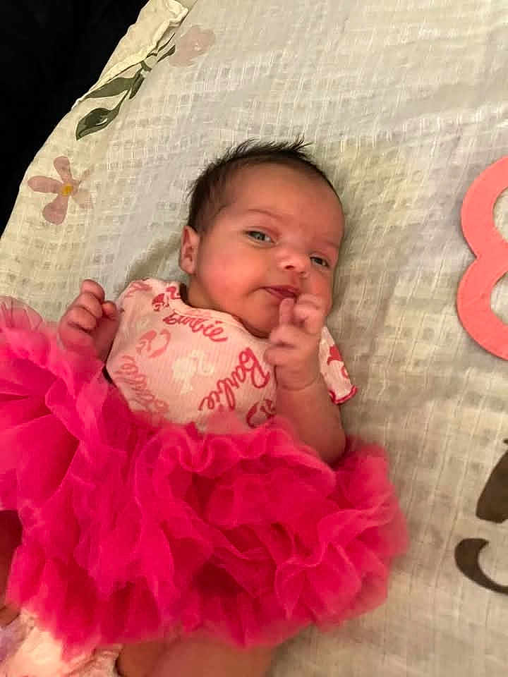 Ruby is registered to the contest to win money with this photo: baby, barbie_onesie, blanket, child, clothing, curious_expression, cute, face, hand, head, indoor, infant, lying_down, newborn, patterned_blanket, pink_tutu, portrait, resting, small_hands, soft_texture