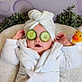 baby, child, cucumber_slices, white_robe, towel_turban, rubber_duck, bath_toy, spa_day, relaxation, facial_mask, cute, indoor, plush_surface, greenery, smiling, person, skin_care, funny, comfort, headwear