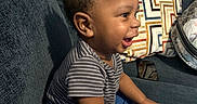 Kevarious joined the competition — help win amazing prizes! toddler, child, smiling, indoor, couch, striped_shirt, blue_pants, pillow, geometric_pattern, phone, happy, sitting, person, furniture, home, casual, cute, young_child, joyful, portrait