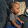 toddler, child, smiling, indoor, couch, striped_shirt, blue_pants, pillow, geometric_pattern, phone, happy, sitting, person, furniture, home, casual, cute, young_child, joyful, portrait