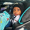 baby, child, car_seat, blanket, hat, beanie, pom_poms, clothing, seatbelt, infant, car_interior, window, toy, blue_blanket, cute, portrait, young_child, sitting, warm_clothing, indoor