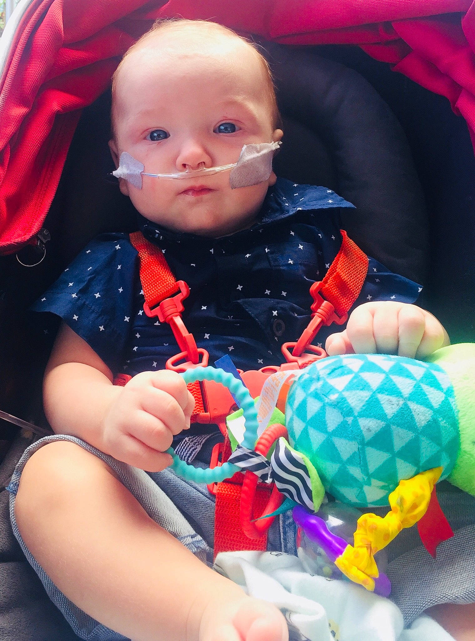 Isaiah is registered to the contest to win money with this photo: baby, baby_products, baby_toys, cheek, child, eye, finger, fun, lip, person, pink, plaid, play, product, red, sitting, skin, smile, textile, toddler