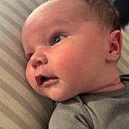 William joined the competition — help win amazing prizes! baby, infant, face, skin, expression, drool, pillow, striped, clothing, grey_shirt, blue_text, person, child, young, cute, portrait, laying, indoors, head, ear