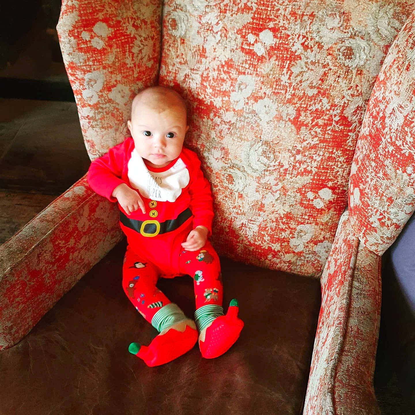 Olivia is registered to the contest to win money with this photo: baby, baby_toddler_clothing, child, comfort, fictional_character, flooring, fun, happy, human_leg, leg, linens, orange, outerwear, pattern, person, red, sitting, sleeve, t_shirt, toddler
