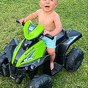 Maxime a rejoint le concours — aidez-le/la à gagner de superbes lots ! barefoot, black, blue_eyes, child, fun, grass, green, hands, happy, head, nature, outdoor, play, quad_bike, shorts, skin, smiling, summer, toddler, toy_vehicle
