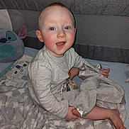 Jackson joined the competition — help win amazing prizes! baby, blanket, child, clothing, comfort, cozy, crib, cute, face, happy, head, indoors, infant, pacifier, person, plush_toy, sitting, smiling, soft_toy, young_child